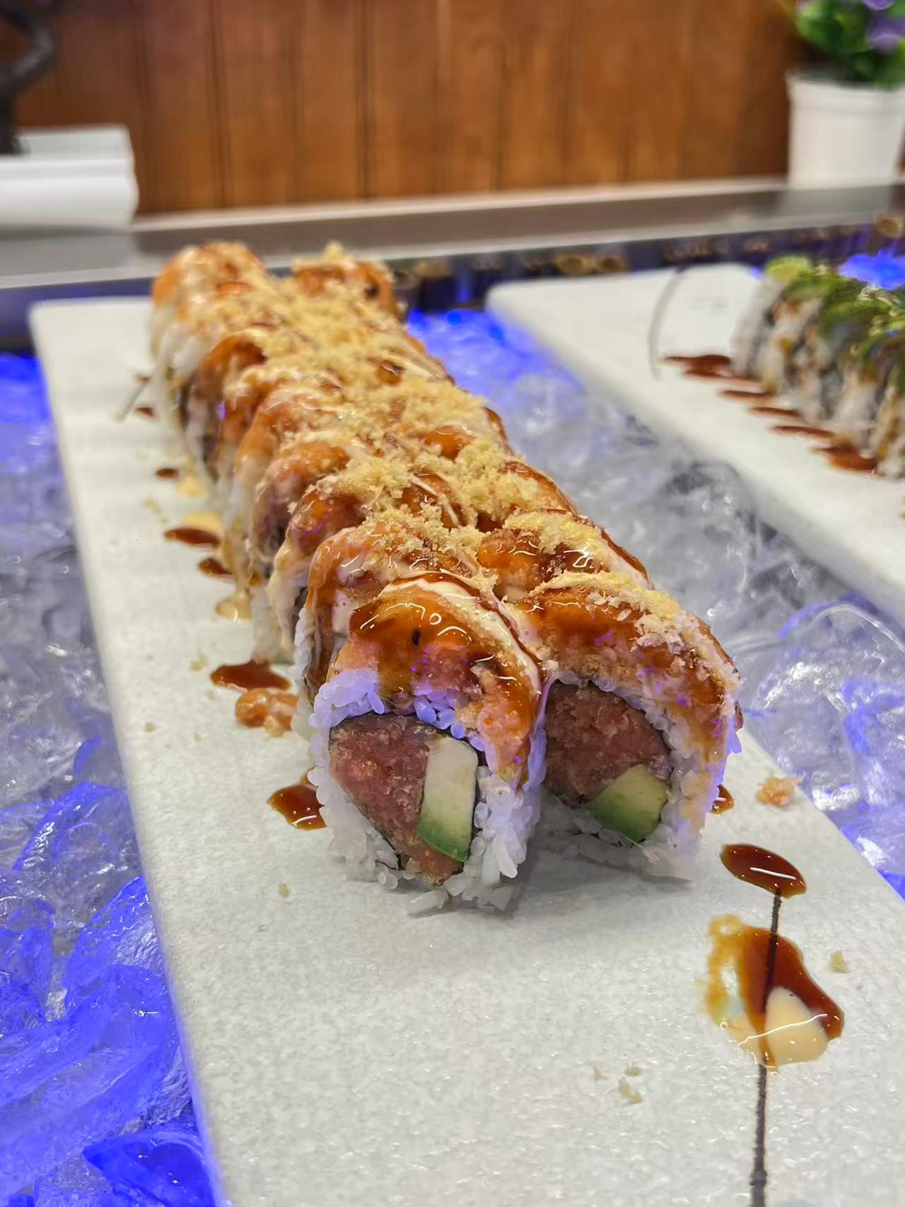 Salmon-topped sushi rolls with sauce and crunchy topping at Kyushu Buffet
